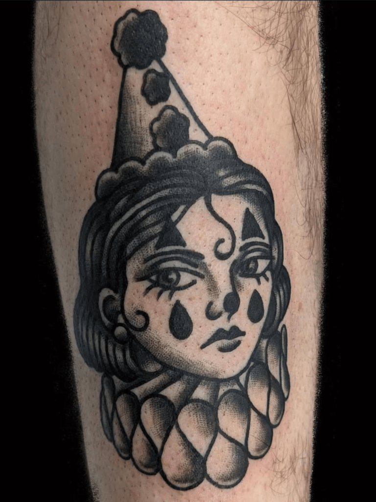 A black and grey American Traditional tattoo of a crying clown girl.