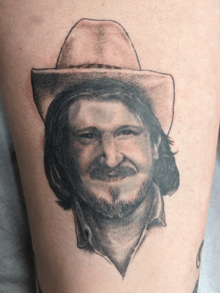 Black and grey realistic tattoo of country singer Willie Carlisle.